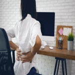 How can you avoid back pain while standing at work?